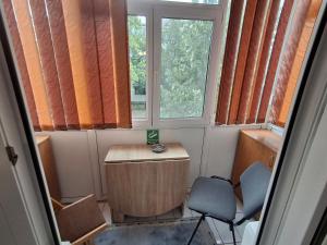 Zimmer mit 2 Stühlen, einem Schreibtisch und 2 Fenstern in der Unterkunft Apartament 2 Camere, Etaj 1 in Buzău
