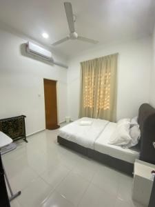 a white bedroom with a bed and a window at Cerah Homestay in Kampong Gong Kempas