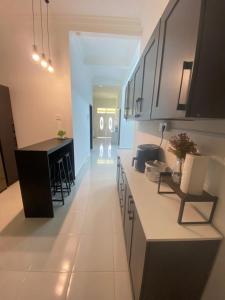 a kitchen with white counters and a black island at Cerah Homestay in Kampong Gong Kempas
