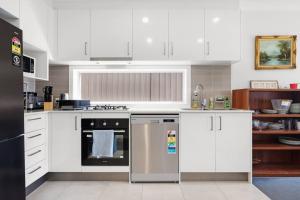 a kitchen with white cabinets and a stainless steel dishwasher at KozyGuru | Austral | Convenient 4 x Ensuite House in Austral +7 photos