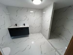 a bathroom with a sink and white marble walls at U maďarčika in Prituľany +49 photos