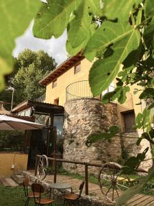 a building with a stone wall and chairs in a yard at Alberg rural torre del baró in Sant Llorenc de Morunys