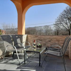 a patio with three chairs and a table with a bottle of wine at Charming Apartment Angela near Malinska in Sveti Anton