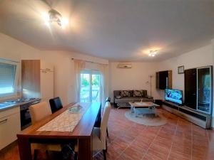 a kitchen and living room with a table and a television at Charming Apartment Angela near Malinska in Sveti Anton +15 photos