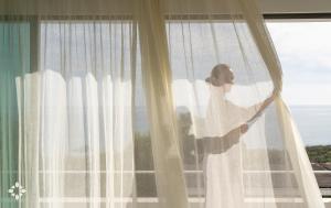 a bride is looking out of a window at Villa EL Azahar by Abahana Luxe in Altea la Vieja