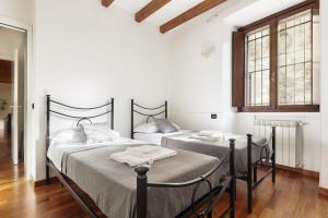 two beds in a white room with two windows at A Due Passi dal Lago in Pusiano