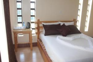a bed in a room with a table and windows at Eshborns House - Near Jomo Kenyatta International Airport and SGR with shuttle services at an extra fee in Nairobi