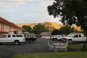 a group of vehicles parked in a parking lot with a mountain at Ephrata Inn Motel in Ephrata