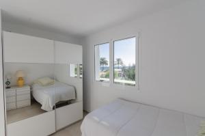 a white bedroom with a bed and two windows at Terraced 2 bedroom beach rental in Maspalomas