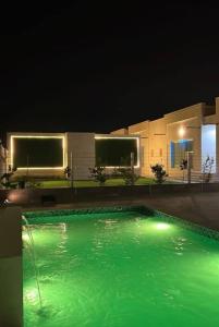 a swimming pool with green water at night at White Garden in ‘Ayn al Fayḑah