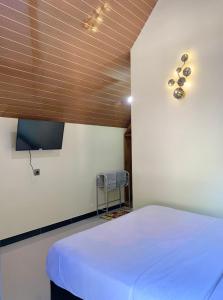 Un dormitorio con una cama blanca y un televisor. en Gubuk Ndeso Bromo, en Bromo