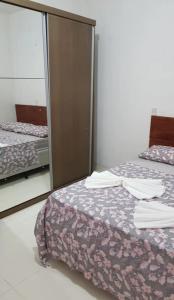 弗洛里亚诺波利斯Casa Florianópolis térreo Rio Vermelho的有两张床和一面镜子的卧室