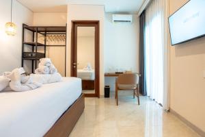 a hotel room with a bed and a television at Miles Coliving Bali, close to Seminyak and Canggu in Kerobokan