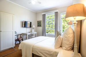 a bedroom with a white bed and a lamp at Sandown Lodge in Cape Town