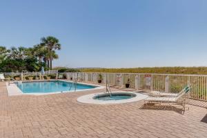 a patio with a swimming pool and a chair at Vibrant Navarre Condo Pool and Beach Chair Service! in Navarre