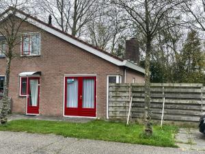 ein Backsteinhaus mit roten Türen und einem Zaun in der Unterkunft Strandparel 381 in Breskens + 8 Fotos