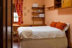 a bedroom with a bed with white sheets and orange pillows at Casa los toriles in Ortigosa del Monte