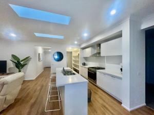 a kitchen and living room with white cabinets and a blue ceiling at Brand New House in Lakes Entrance in Lakes Entrance