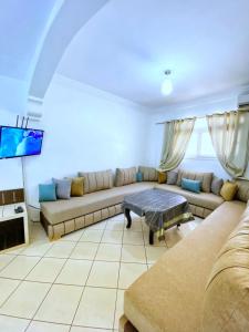 a living room with a couch and a tv at Terrasseplage appartement N9 in Tamraght Ouzdar