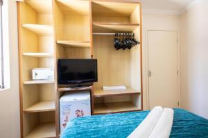 a room with a bed and a tv and shelves at Villas diRoma - Hotéis com roupa de cama e um dia de ACESSO ao diRoma Acqua Park--DESTINOS COMBINADOS TURISMO in Caldas Novas