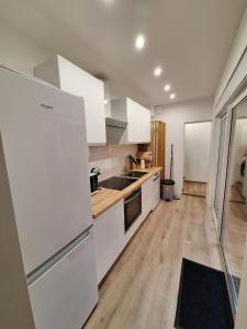 a kitchen with white appliances and a wooden floor at Le Petit Chez Soi maison in Calais