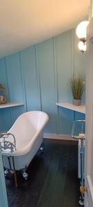 a bathroom with a tub and a blue wall at The Studio Trewarveneth Manor Farm TR185NF in Newlyn +14 photos