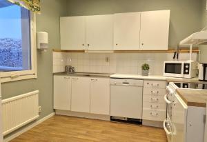 a kitchen with white cabinets and a microwave at Kuttainen Lodge in Karesuando