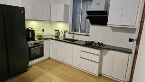 a kitchen with white cabinets and a black refrigerator at Kandy home in Kandy