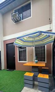 a table with an umbrella in front of a house at Fully-furnished House Near Puan, Bago & Baliok in Davao City in Davao City