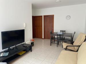 a living room with a flat screen tv and a table at Apartamento Santos in Ribeira Grande
