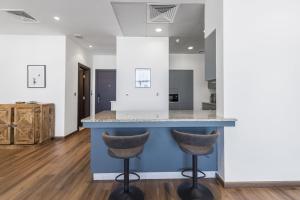 a kitchen with a blue island with two bar stools at Emerald at Tiara Beach Residences with Atlantis views in Dubai