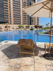 a chair under an umbrella next to a swimming pool at Emerald at Tiara Beach Residences with Atlantis views in Dubai