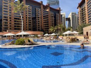 a large swimming pool with chairs and umbrellas at Emerald at Tiara Beach Residences with Atlantis views in Dubai