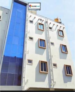 - un bâtiment blanc avec des fenêtres et un panneau indiquant la rue dans l'établissement Qubenest Elite Manyata Tech Park, à Bangalore