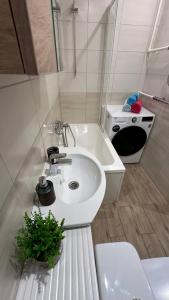 a white bathroom with a sink and a bath tub at Studio apartment in Valmiera