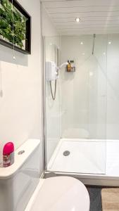 a white bathroom with a shower and a toilet at Flat for 6 guests near Glasgow, Loch Lomond in Dumbarton +34 photos
