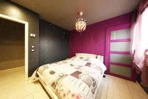 a bedroom with a bed and a purple wall at Bretzel Home in Colmar