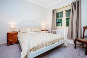 Un dormitorio con una cama blanca y una ventana. en Allambee Cottage - a place of rest, en Katoomba