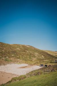 a beach on a hill next to a field at Polzeath Beach House in Polzeath