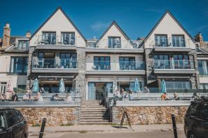 a large stone building with people sitting in front of it at Polzeath Beach House in Polzeath