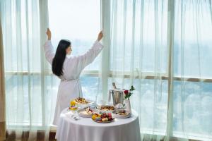 a woman standing in front of a table with food at Grand Millennium Al Wahda Hotel and Executive Apartments Abu Dhabi in Abu Dhabi