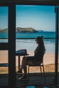a woman sitting in a chair in front of the beach at Polzeath Beach House in Polzeath