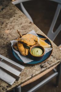 a plate of food with a sandwich and dipping sauce at Polzeath Beach House in Polzeath