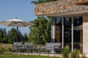 a group of chairs and an umbrella on a patio at Lodge Tunuyan, Destino Uconia in Vista Flores