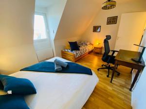 a bedroom with a large bed and a desk and a computer at Escale à Balbec- Proche plage et Centre ville Cabourg in Cabourg
