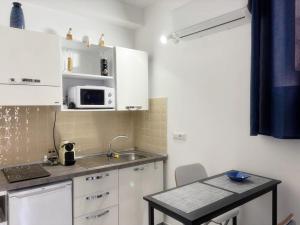 a kitchen with white cabinets and a table and a microwave at San Giovanni Apartment in Catanzaro +18 photos