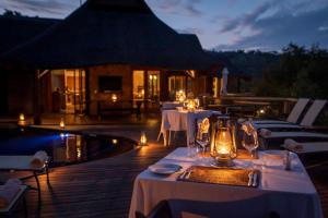 a restaurant with white tables and chairs next to a pool at Tshwene Lodge in Vaalwater