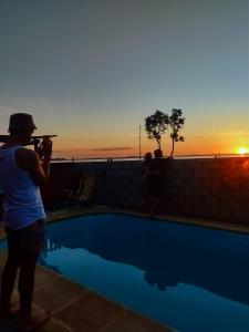 チャスコムスにあるLoft Puesta de Sol mágica vista a la laguna y sus atardeceresのプールサイドで夕日の写真を撮っている男性