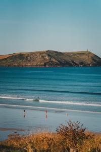a beach with people swimming in the water at Polzeath Beach House in Polzeath
