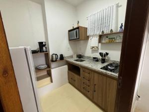 a small kitchen with a sink and a microwave at Cantinho do Mané in Florianópolis